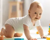 Bebé de 3 meses gateando, rodeado de bloques de colores y un apilador de aros, ideal para estimular su desarrollo.