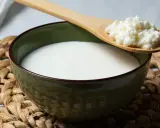 Un bol de kéfir, un probiotique naturel pour soulager le ballonnement, avec une cuillère en bois contenant des grains de kéfir.