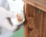 Guante de látex retirando barniz de un mueble de madera. Proceso para decapar un mueble lacado.