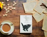 Libro "If Cats Disappeared From The World" con un gattino nero, occhiali, fiori e una tazza di tè. La trama esplora un mondo senza gatti.