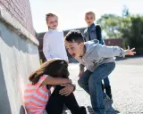 Niña acosada por otros niños en la calle.