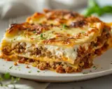 En bit krämig lasagne med köttfärs och bechamelsås, toppad med gyllene ost.