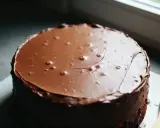 Gâteau rond recouvert d'un glacage chocolat noir brillant, avec quelques bulles d'air.