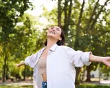 Jeune femme rayonnante dans un parc, profitant de la nature. Elle semble ressentir les bienfaits de la L-tyrosine pour son bien-être.