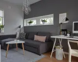 Snyggt hemmakontor med mörkgrå vägg, soffa, skrivbord och dator. Inspiration för ett modernt och stilrent arbetsrum.