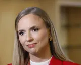 Sara Skyttedal, med sitt blonda hår och röda kavaj, ler snett mot kameran.