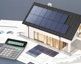 Calculatrice, graphiques et maison avec panneaux solaires, illustrant la rentabilité panneau solaire.