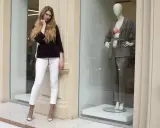 Modelka w białych spodniach i bordowej marynarce obok manekina w eleganckim stroju. Skandynawskie marki odzieżowe prezentują najnowsze trendy.