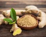 Des racines de gingembre frais et de la poudre de gingembre dans un bol en bois. Le gingembre est-il aphrodisiaque ? Une question qui suscite la curiosité.