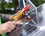 Instalator sprawdza panel fotowoltaiczny miernikiem. To krok do skorzystania z ulgi na odliczenie fotowoltaiki od podatku.