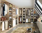 Un dressing bien organisé pour savoir comment ranger son dressing : vêtements suspendus, étagères remplies, tiroirs et accessoires à portée de main.