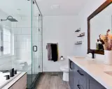 Baño moderno con ducha de cristal, inodoro, lavabo doble y un gran espejo. Las ventanas para baños pequeños son clave para la luminosidad.