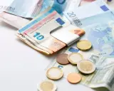 Euro banknoty i monety, czyli waluta w Grecji. Widać banknot 10 euro w metalowym klipsie, a obok monety i banknoty 5, 20 euro.