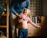 Padre viste a su hijo, quien ríe a carcajadas. A pesar de que mi hijo cada vez se porta peor, estos momentos son oro.