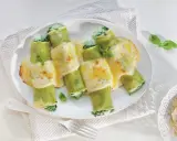 Zielone cannelloni ze szpinakiem, zapieczone pod kremowym sosem serowym, ozdobione listkami bazylii.