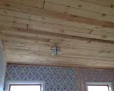 Taket består av obehandlad furu, perfekt för den som vill måla obehandlad furu inomhus. En taklampa hänger från det rustika träet.
