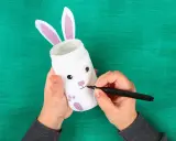 Mani che creano un coniglietto pasquale con un barattolo, un'idea per lavoretti di Pasqua facili maestra Mary.