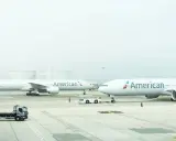 Dwa samoloty American Airlines na płycie lotniska, gotowe do przyjęcia bagażu rejestrowanego.