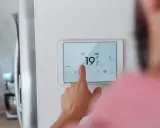 Main d'une personne ajustant la température sur un écran tactile, optimisant la programmation chauffage pour un confort idéal.