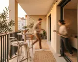 Un balcone piccolo abbellito con piante, un tavolino, sedie e luci. Perfetto per godersi momenti all'aperto.