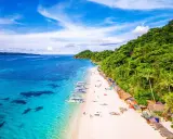 Rajska plaża na Filipinach z turkusową wodą, białym piaskiem i zielonymi wzgórzami.