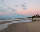 Zachód słońca nad morzem w Łebie. Piękne łeba atrakcje, plaża, zamek i spacerujący ludzie.