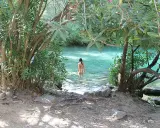 Una mujer se baña en la cueva del gato, un oasis de aguas cristalinas rodeado de vegetación exuberante.