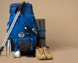 Niebieski plecak trekkingowy, kije, buty, mata, kompas, krótkofalówka i termos – wszystko gotowe na wyprawę.