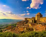 Un borgo toscano al tramonto, con tetti in cotto e un campanile svettante. Curiosità sulla Toscana: questo paesaggio evoca storie antiche.