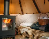 Mysig moskoselkåta med sprakande kamin, renskinn och en korg med tofflor.