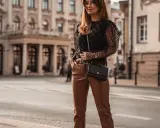 Elegancka stylizacja: czarna bluzka w kropki i brązowe skórzane spodnie. Idealne połączenie, by zadać pytanie: jaka bluzka do skórzanych spodni?