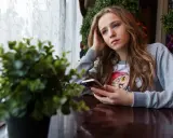 Dziewczyna z telefonem, zamyślona, być może czeka na wiadomość od przyjaciela, pielęgnując swoją relację platoniczną.