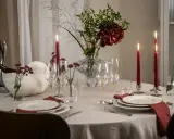 En vacker dukning med röda ljus, blommor och glas. En perfekt inramning för en mysig middag.
