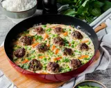 Herzhafte Fleischbällchen in cremiger Sauce mit Erbsen und Karotten, ein köstliches Wikingertopf Rezept, serviert in einer roten Pfanne.