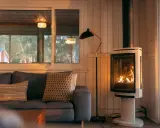 Un poêle à bois moderne chauffe une pièce cosy. Respectez la distance à respecter autour d'un poêle à bois pour une sécurité optimale.