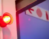 Czerwony alarm przeciwpożarowy miga, przypominając o tym, co to dysocjacja. Znak ewakuacyjny w tle.