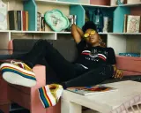 Une jeune femme aux lunettes rondes dorées se détend sur un canapé, ses chaussures arc-en-ciel colorées bien en évidence. Elle incarne le parfait "chill traduction".