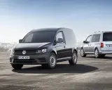 Dos furgonetas Volkswagen Caddy, una negra y otra plateada, demuestran su versatilidad como vehículo mixto adaptable en un entorno portuario.