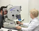 Lekarz wykonuje badanie wzroku pacjentowi na nowoczesnym sprzęcie. Przed badaniem angiografia fluoresceinowa przeciwwskazania są kluczowe.