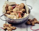 Un cuenco lleno de galletas de jengibre con caritas sonrientes y corazones, atadas con hilo rojo y blanco.