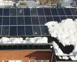 Snö täcker delar av solpanelerna på ett tak. Snart är det dags att skotta solpaneler för att fånga solens energi igen.