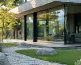 Una moderna casa con una **ventana panorámica** que refleja el verde jardín y los árboles.