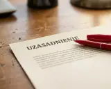 Czerwony długopis leży obok dokumentu z nagłówkiem "UZASADNIENIE". Może to być kluczowy dokument, który wymaga przemyślenia przed złożeniem wypowiedzenia.