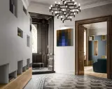 Ingresso con armadiature moderne, lampadario geometrico e un quadro astratto, in un ambiente che evoca lo stile liberty moderno.