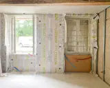 Pose de pare-vapeur pour comment isoler un mur intérieur. Fenêtres, tuyaux et ossature métallique visibles.