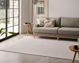 Un salón moderno con un sofá gris, una alfombra de diseño y una mesa auxiliar.