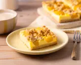 Ein Stück saftiger Pfirsich Blechkuchen mit Vanillepudding und Streuseln auf einem gelben Teller, daneben eine Gabel.