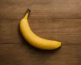 Eine gelbe Banane liegt auf einem Holztisch. Sie ist ein gesunder Snack, aber wie viel Protein hat eine Banane?