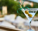 Elegancki kieliszek martini z dwiema oliwkami i zieloną ozdobą. Idealny na toast "cin cin fiero" w letni wieczór.