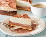 Pyszna tarta z mascarpone i czekoladą, posypana kakao, czeka na widelczyk. Obok filiżanka kawy.